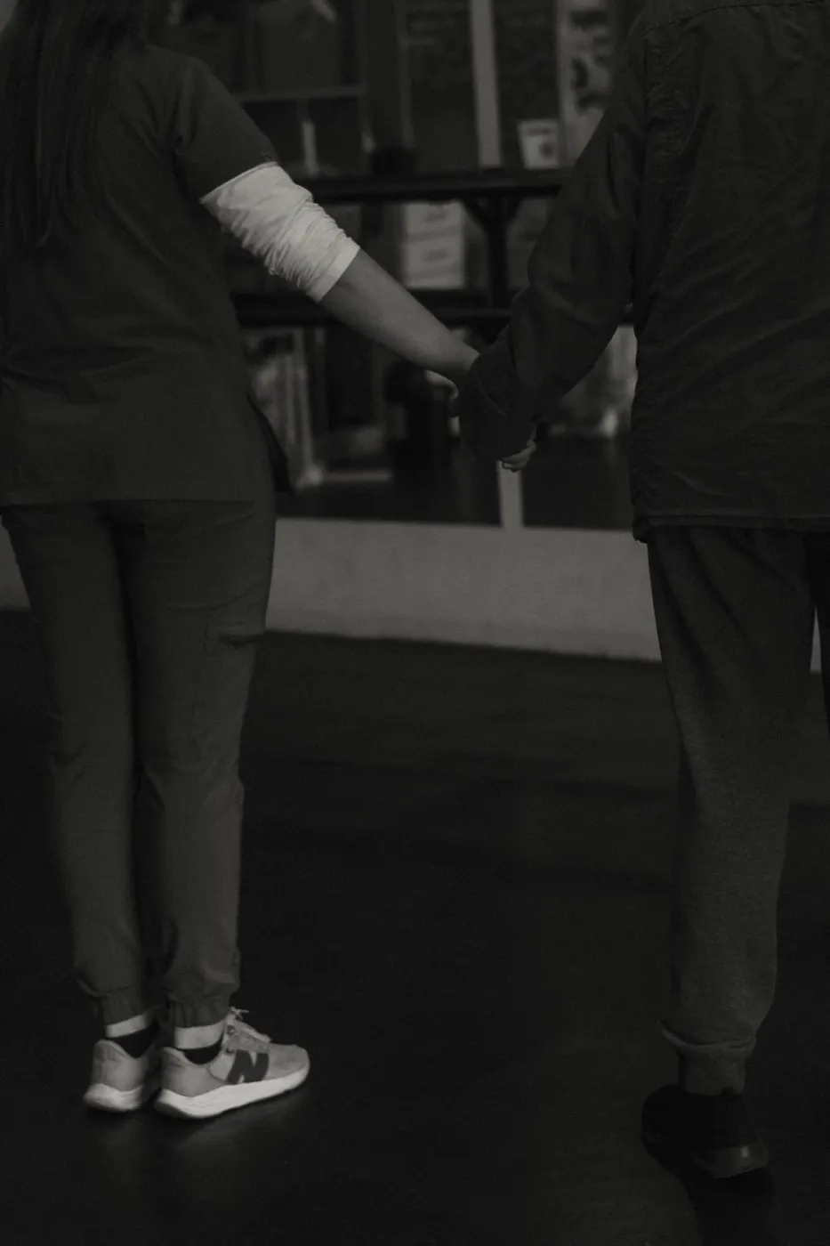 Therapist holding a participant's hand for support during a gentle walking exercise.