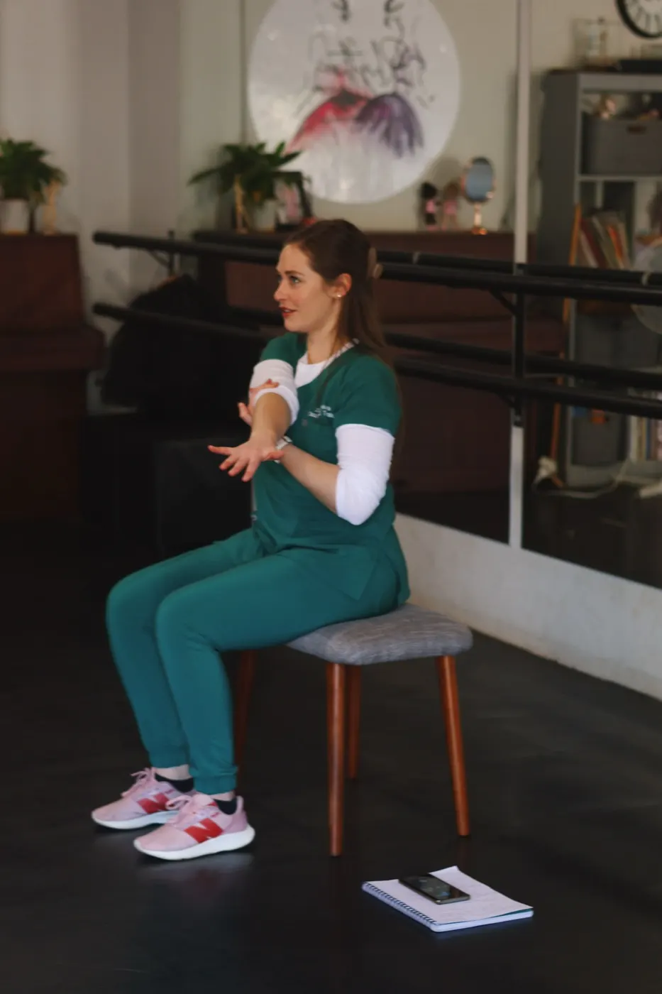 Therapist seated on a stool guiding a gentle arm and hand movement.