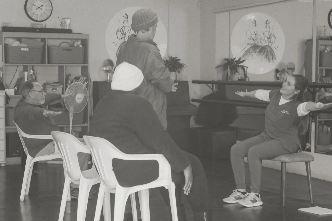 A group session in progress, with participants and the therapist reaching out to the side together.