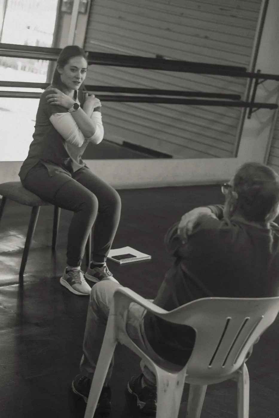 Therapist demonstrating a cross-arm shoulder stretch while a participant watches.